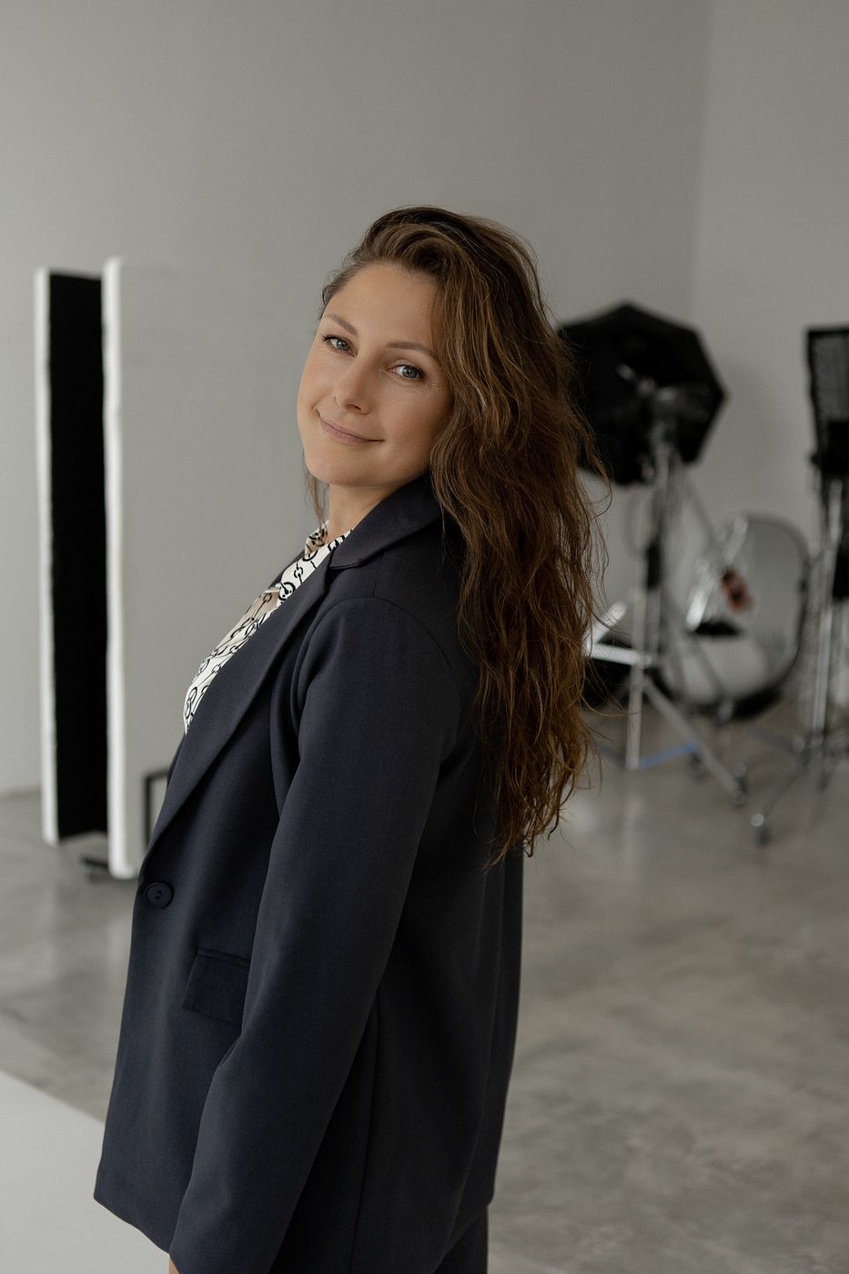 Volha Byrne in a grey suit, turning to look at the camera